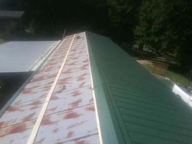 Old rusted panels beside newly installed green metal roofing — Wind Damage Roof Repair by Roofing Brothers in Sandisfield