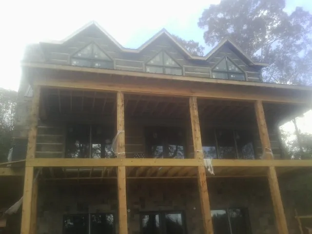 Dormers and porch framing on a large log home under construction — Roof Coating work by our crew in Sandisfield