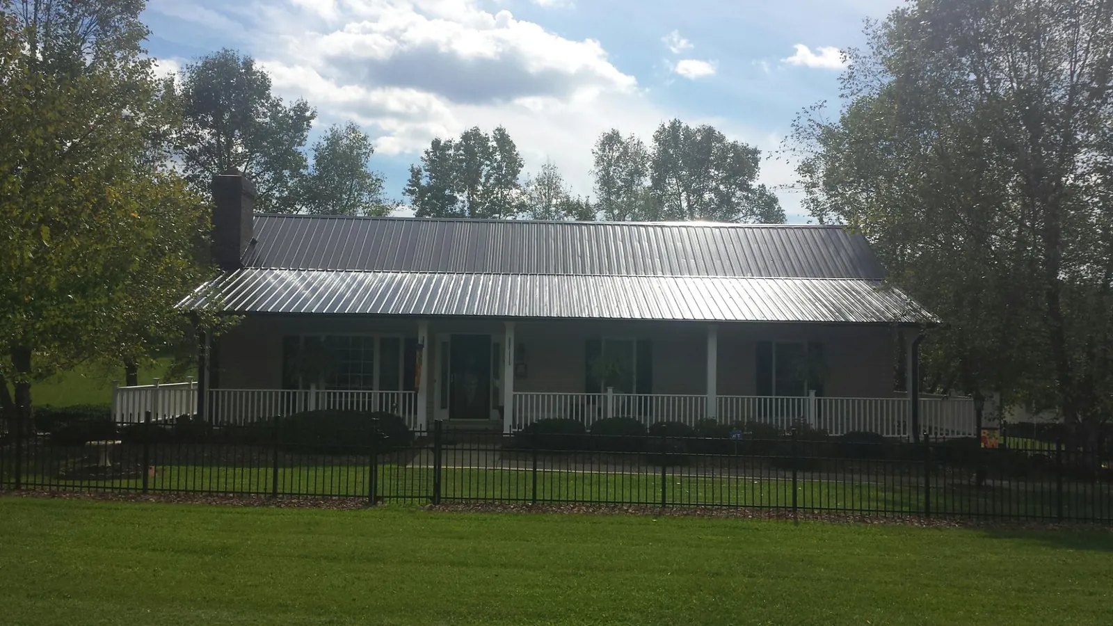 Gray metal roof on a brick ranch with a full width front porch — Gutter Guard Installation work by our crew in Sandisfield