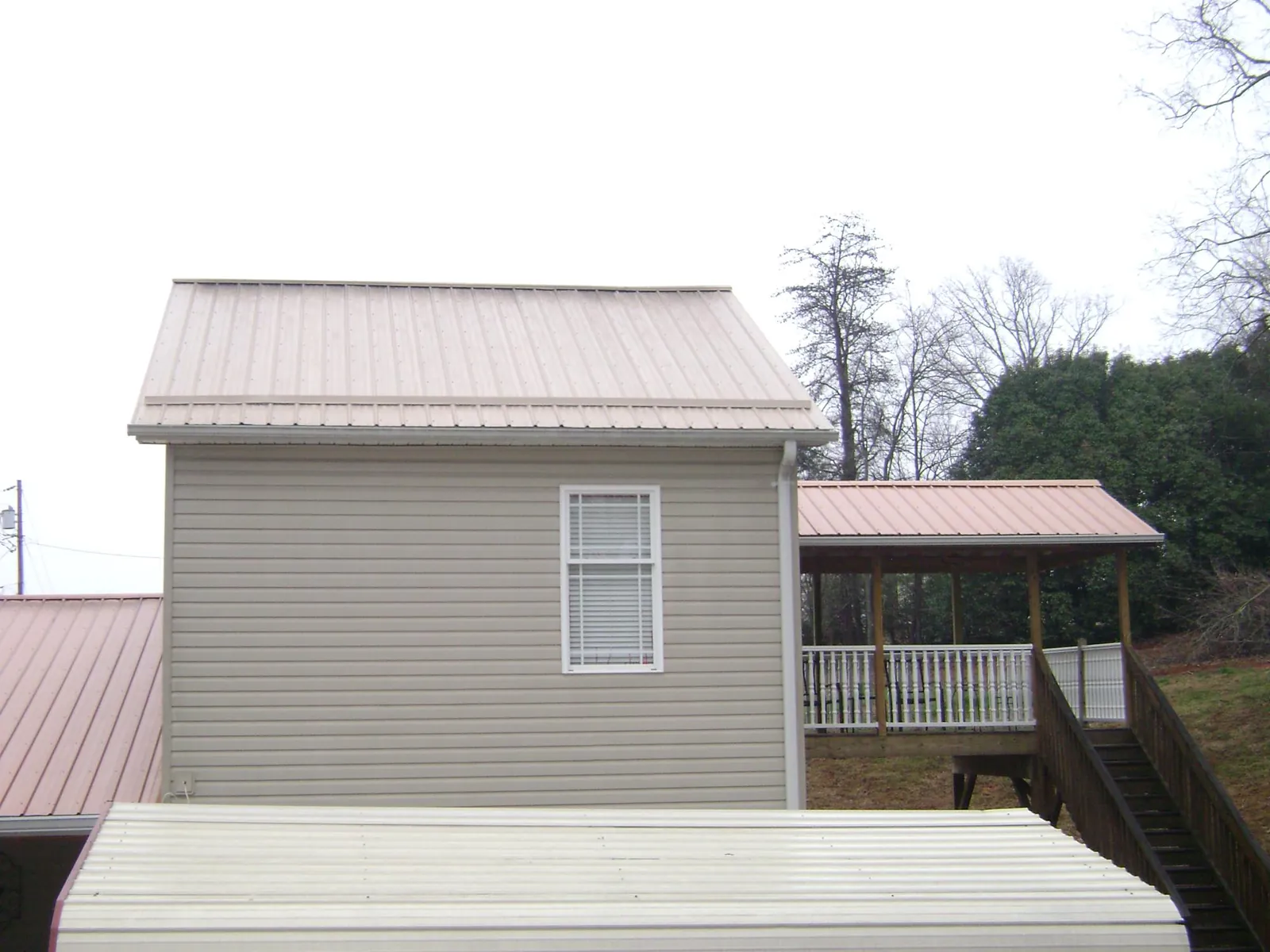 Tan metal roofs on a two story addition and attached porch, from a Roof Replacement job in Sandisfield