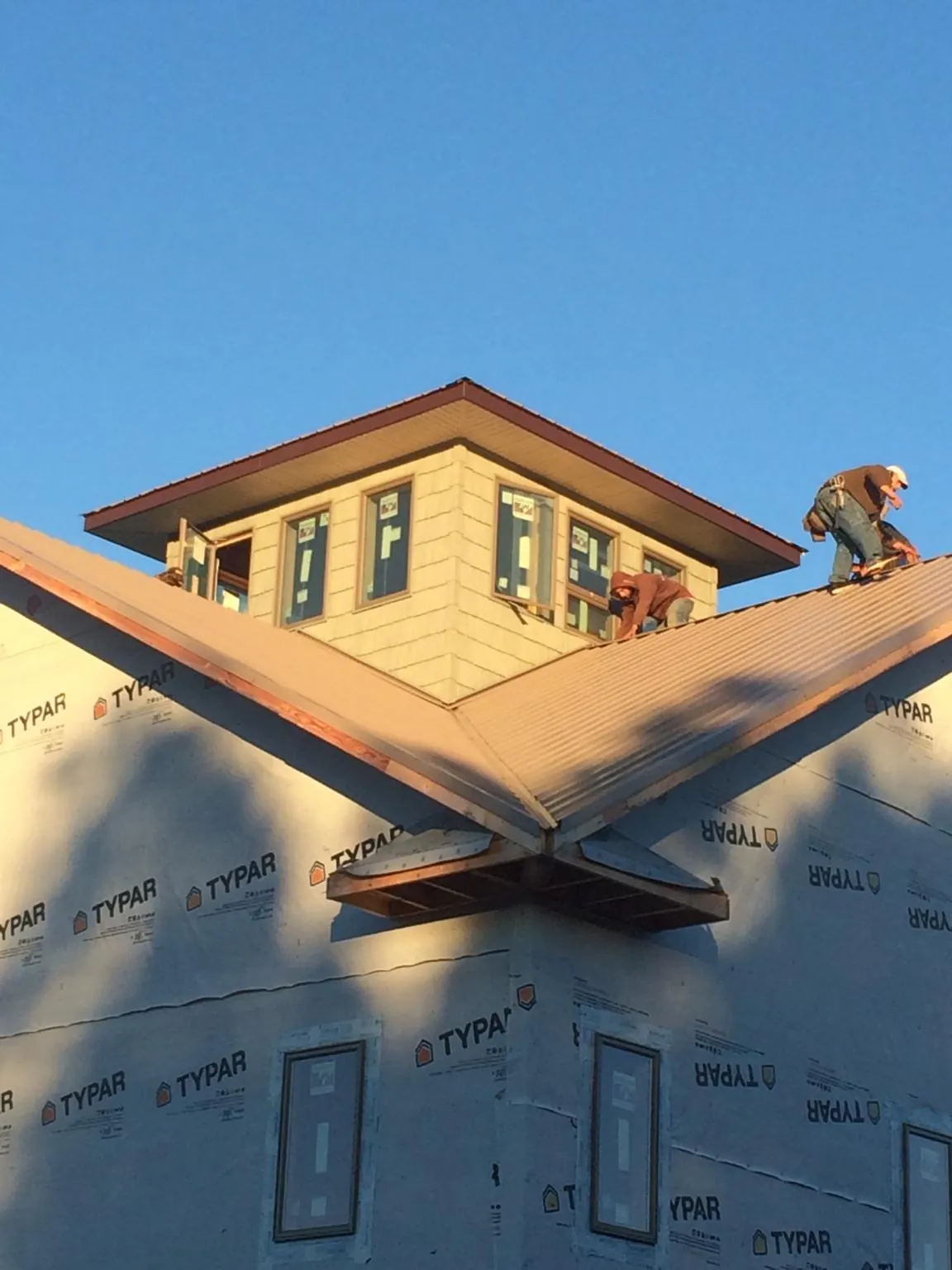 Roofers working around a rooftop cupola on a new metal roof at sunset — Roof Waterproofing in Sandisfield by Roofing Brothers